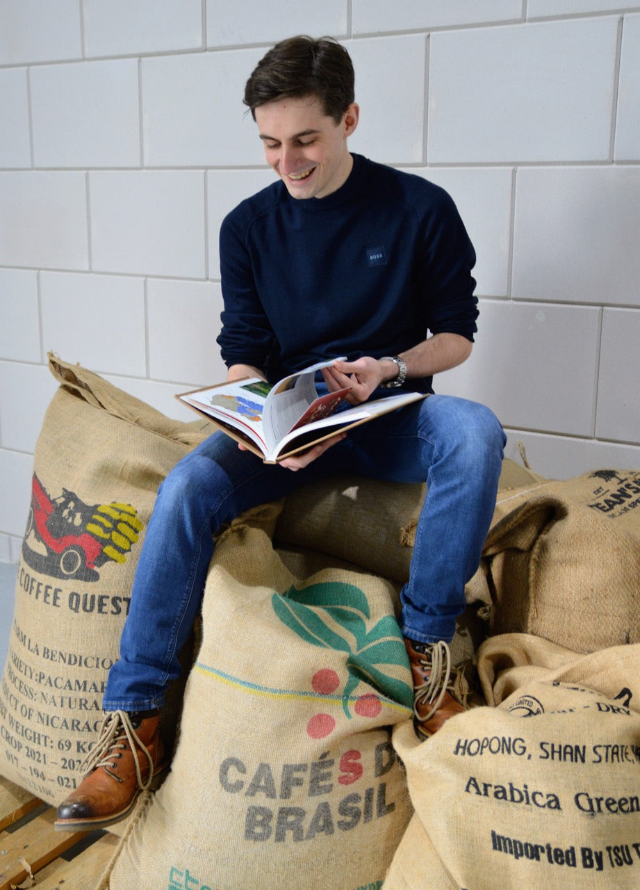 Vincent op balen koffiebonen met boek in hand