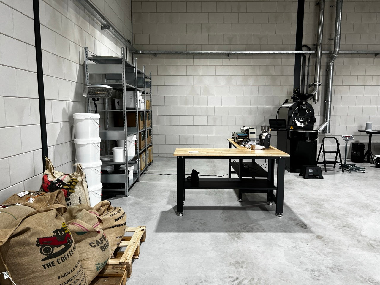 Overzicht van de branderij, met voorraad, inpakruimte en de koffiebrander P05 van Probat op de achtergrond