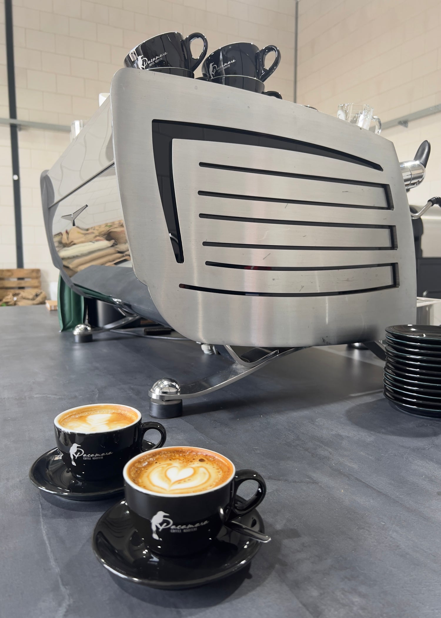 Twee cappuccino's met latte art naast een espressomachine 