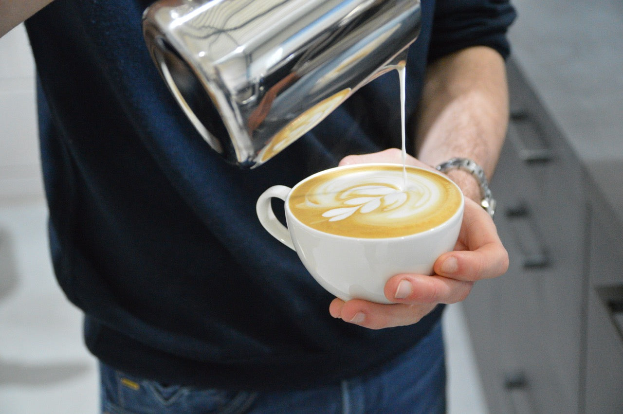 Cappuccino die wordt ingeschonken met latte-art